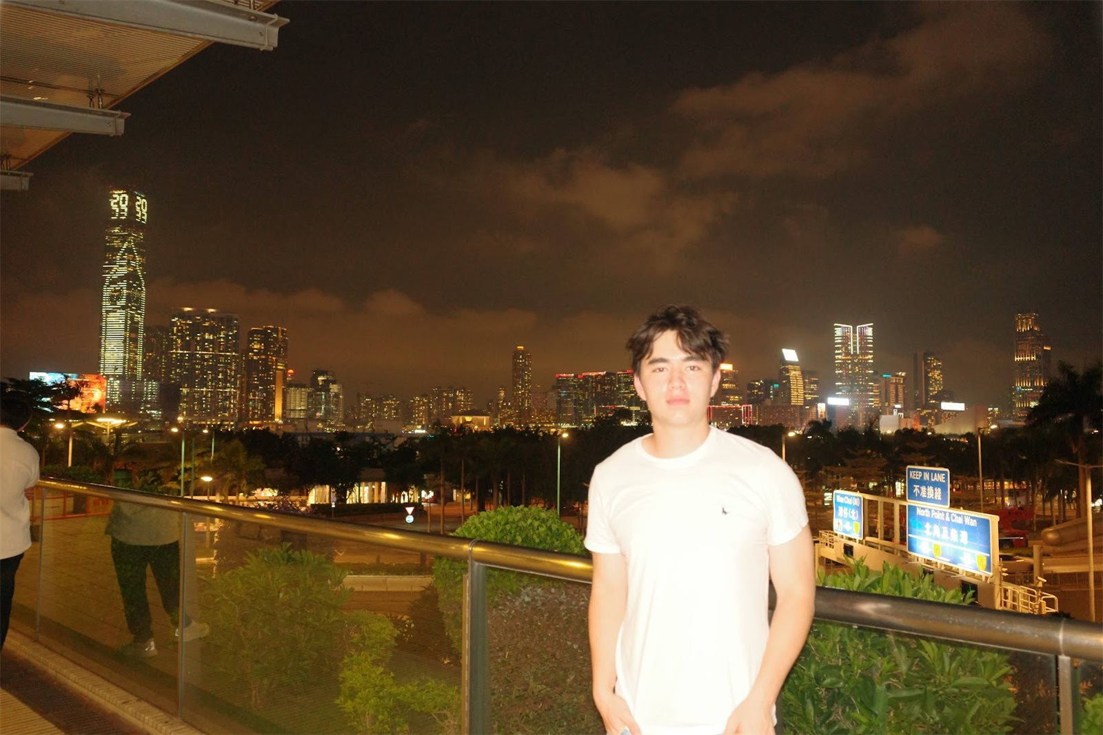 Gavin standing at a railing in front of the Hong Kong skyline at night